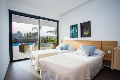 two beds in a bedroom with a view of a pool at Villa Macán in Teguise