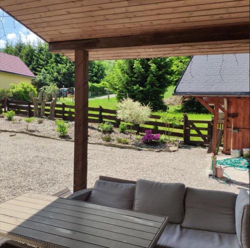 une terrasse avec un canapé sous une pergola en bois dans l'établissement Dom nad rzeką, à Nowy Gierałtów