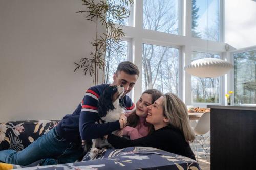 a man and two women laying on a couch with a dog at Chalet Villa Bianca Spa in Sainte Béatrix