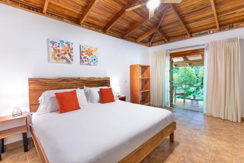 een slaapkamer met een groot wit bed met oranje kussens bij Makanas Beach Bungalows in Santa Teresa Beach