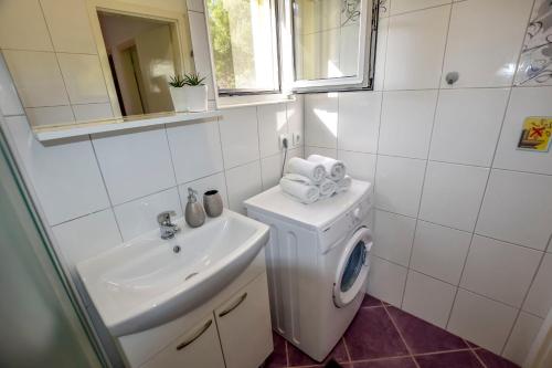 biała łazienka z umywalką i pralką w obiekcie House Ana w mieście Banj