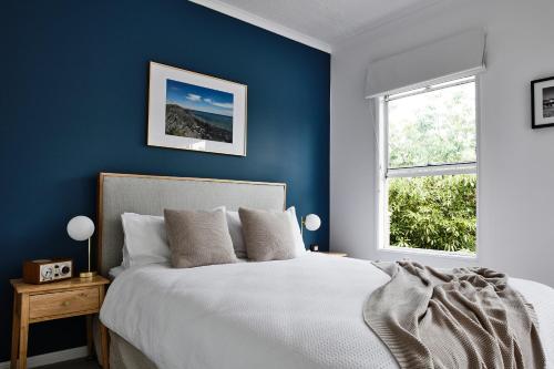 a blue bedroom with a bed and a window at Stylish Townhouse in Melbourne's Playground in Melbourne