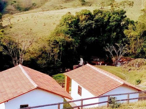 zwei Dächer von zwei Häusern mit einem Hügel im Hintergrund in der Unterkunft Chalés Cachoeira Cafundó in Bueno Brandão