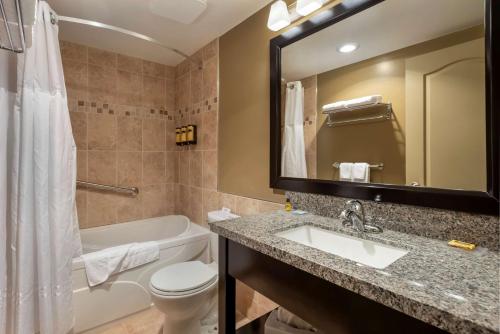 a bathroom with a sink and a tub and a toilet at Best Western Plus Baker Street Inn in Nelson