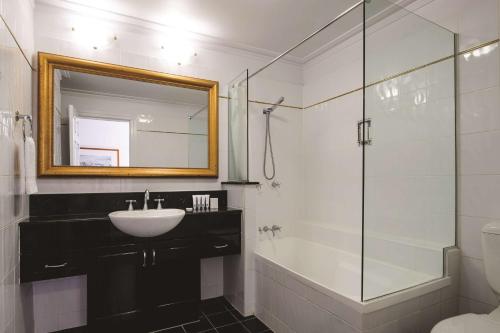 a bathroom with a sink and a glass shower at Adina Apartment Hotel Brisbane Anzac Square in Brisbane