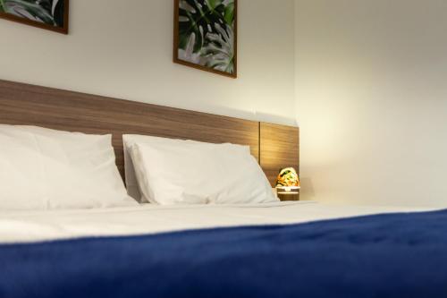 a bed with white pillows and a wooden headboard at Flats Angatu Porto de Galinhas PE in Porto De Galinhas