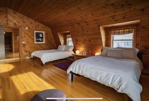 1 dormitorio con 2 camas en una cabaña de madera en Hillside Estate - 14 Acre Waterfront Log home on Lake Champlain, en Grand Isle