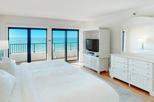 a white bedroom with a large bed and a television at Breakers East 604 in Destin