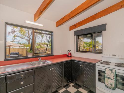 a kitchen with a sink and a stove at Surfscape - Whitianga Holiday Home in Whitianga