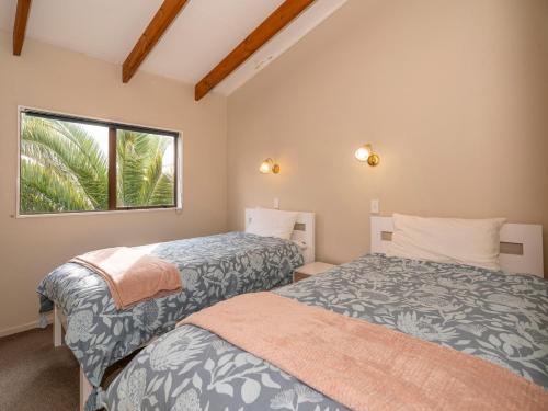 a bedroom with two beds and a window at Surfscape - Whitianga Holiday Home in Whitianga
