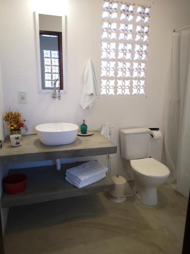 a bathroom with a sink and a toilet and a window at Morada Patacho in Pôrto de Pedras