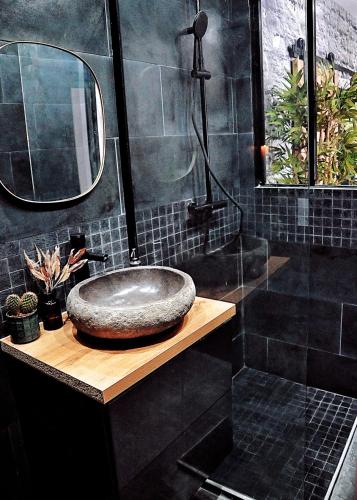 une salle de bain avec un lavabo en pierre et un miroir dans l'établissement L'Evasion romantique en Amazonie, SPA, Écran cinéma, day use, Lit baldaquin, à Évreux