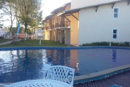 a white chair sitting next to a swimming pool at Village em Condomínio c/ piscina e acesso a praia in Camaçari