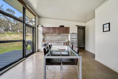 une salle à manger avec une table et des chaises en verre dans l'établissement Ecocrackenback 16 Sustainable chalet close to the slopes, à Crackenback