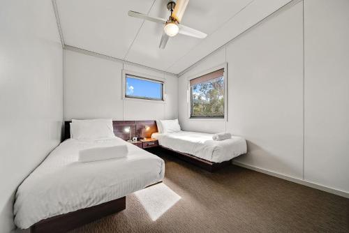 a bedroom with two beds and a ceiling fan at Ecocrackenback 16 Sustainable chalet close to the slopes in Crackenback