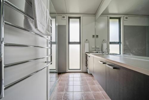 a kitchen with a stainless steel refrigerator and windows at Ecocrackenback 19 Sustainable chalet close to the slopes in Crackenback
