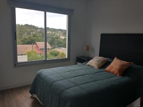 - une chambre avec un lit et une grande fenêtre dans l'établissement Cabañas DORA, à Sierra de los Padres