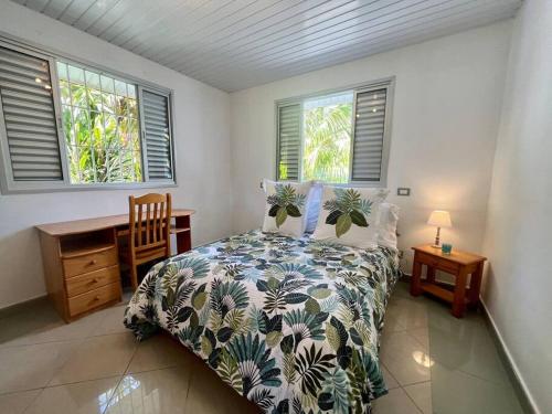 a bedroom with a bed and a desk and windows at Waterfront paradise 2 br; stunning sunsets in Bora Bora