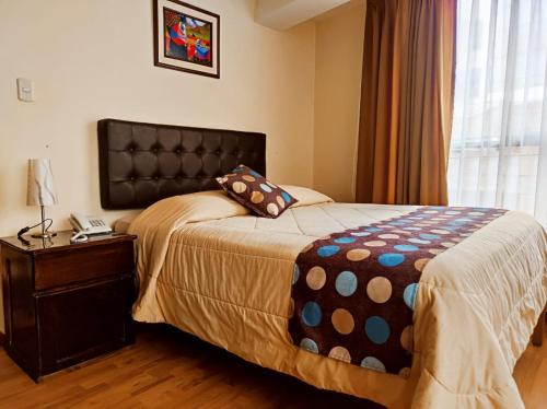 a bedroom with a bed and a table and a window at Algo Mas Hotel - Santa Beatriz in Cusco