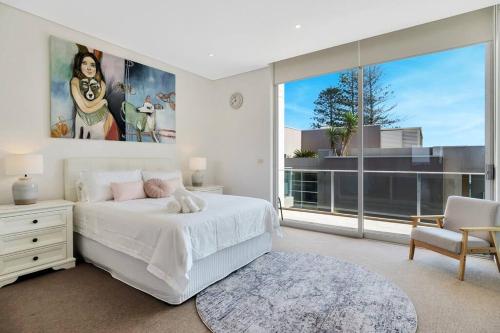 una camera con un letto bianco e una grande finestra di Paradise Penthouse - Beach Front Style and Luxury a The Entrance