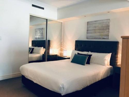 a bedroom with a large white bed and a mirror at Fantastic location - apartment in Sydney CBD BON02617 in Sydney