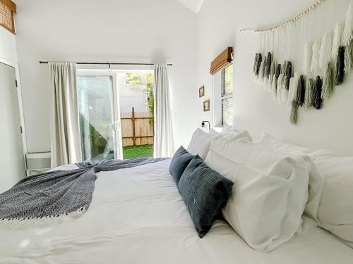 a bedroom with a bed with white sheets and blue pillows at Pristine 1BD/1BA Bungalow + Hot Tub - Ocean Park in Los Angeles