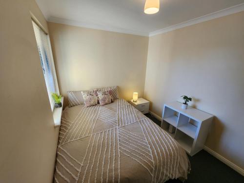 ein kleines Schlafzimmer mit einem Bett und einem Tisch in der Unterkunft Comfortable Villa across the road from the Historic Recreation Hotel in Kalgoorlie