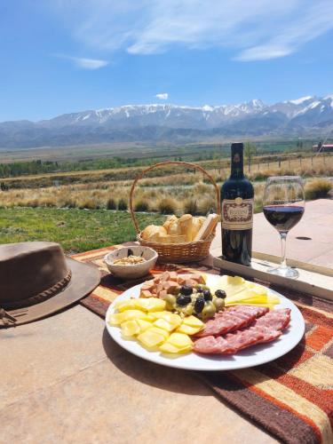 una mesa con un plato de comida y una botella de vino en Casa Pradera de los Andes en Tupungato