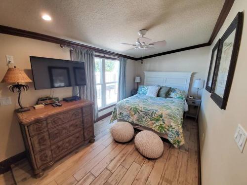 a bedroom with a bed and a flat screen tv at Hawaiian Cottage - Heated Pool Walk to the Beach in Cocoa Beach