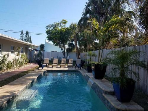 una piscina en un patio con sillas y árboles en Hawaiian Cottage - Heated Pool Walk to the Beach en Cocoa Beach