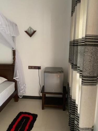a bedroom with a tv and a bed and curtains at Ramesh Guesthouse in Mirissa