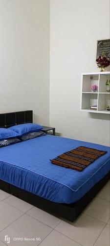 a bedroom with a bed with a blue blanket and a shelf at Rawyna homestay segamat in Segamat