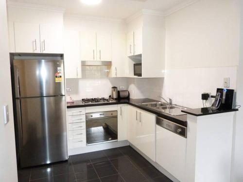 a kitchen with white cabinets and a stainless steel refrigerator at Ultra Convenient Apartment HER09029 in Sydney