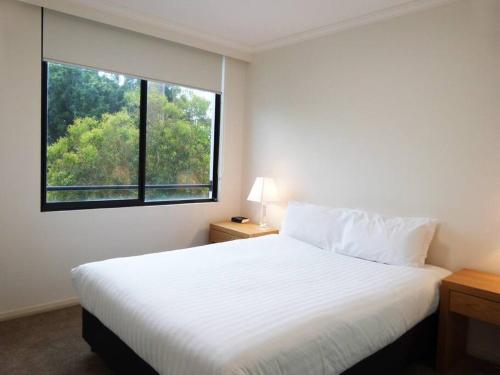 Ultra Convenient Apartment HER09029 في سيدني: غرفة نوم بسرير ابيض ونافذة