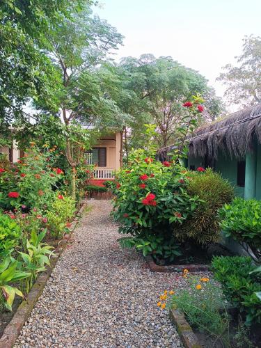a garden with red flowers and a house at Crocodile Safari Camp in Chitwan