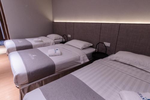 a hotel room with three beds with white sheets at OCEAN HOTEL in Labuan