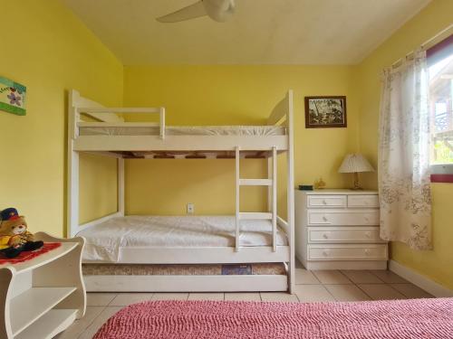 una camera con 2 letti a castello in una camera gialla di Casa Praia da Barra, Garopaba a Garopaba