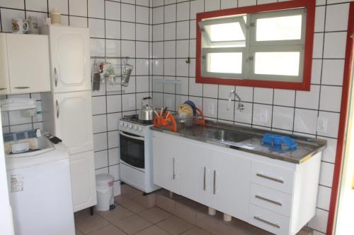 una cucina bianca con lavandino e frigorifero di Casa Praia da Barra, Garopaba a Garopaba