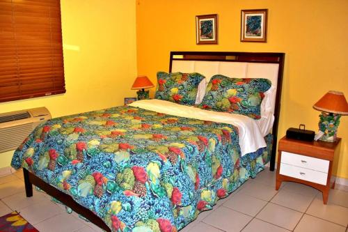1 dormitorio con 1 cama con un edredón colorido en Summer all year! Oceanfront with Pool A/C en Aguadilla