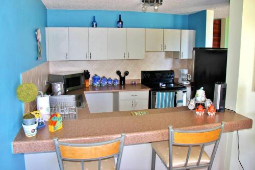 a kitchen with white cabinets and a counter with chairs at Summer all year! Oceanfront with Pool A/C in Aguadilla