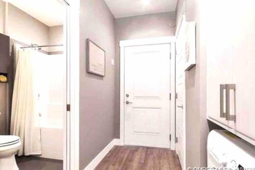 a bathroom with a toilet and a white door at Lovely condo located close to downtown/waterfront! in Kelowna