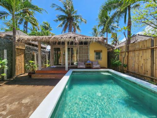 a villa with a swimming pool in front of a house at Bamboo Lodge 2 in Gili Trawangan