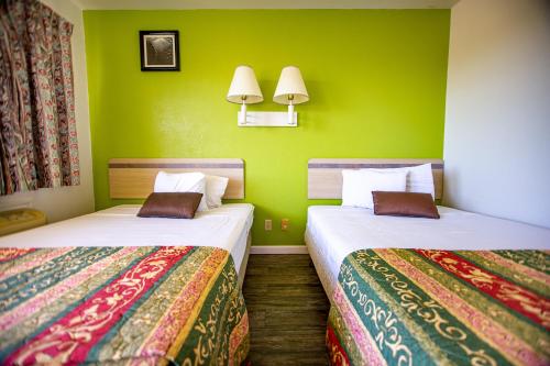 two beds in a room with green walls at Marifah Inn Sweetwater in Sweetwater