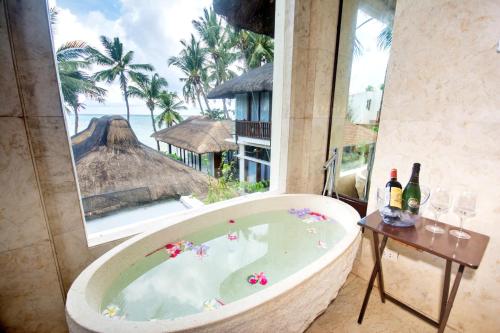 a bath tub in a room with a view of the ocean at Harlan Beach Villa Boracay in Boracay