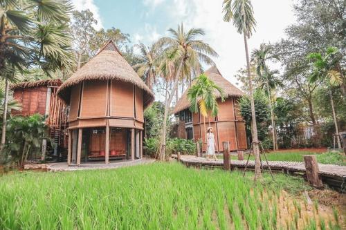 une femme debout devant un bâtiment avec des palmiers dans l'établissement LA A NATU Pranburi, à Sam Roi Yot