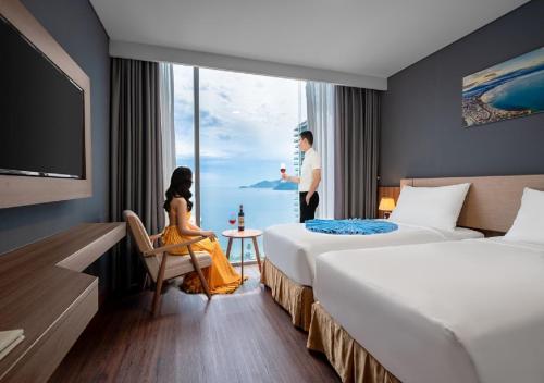 a hotel room with two beds and a man looking out the window at Libra Hotel Nha Trang in Nha Trang