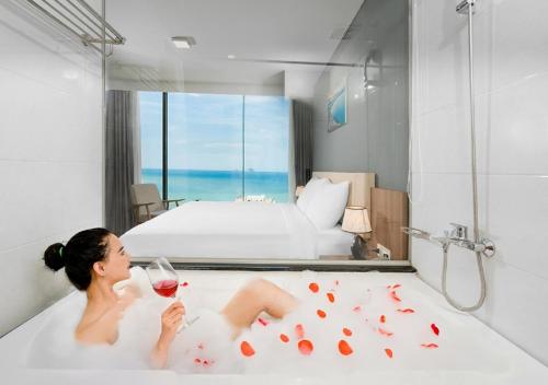 a woman laying in a bath tub with a glass of wine at Libra Hotel Nha Trang in Nha Trang
