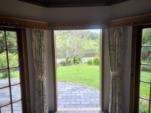 an open glass door with a view of a yard at The Bridge House with private pool and jetty in Mangonui