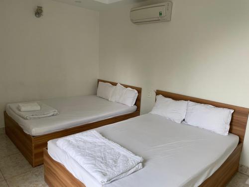 2 bedden in een kamer met witte lakens bij Ky Phu in Thuan An