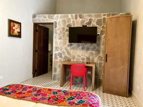 Cette chambre dispose d'une table, d'une chaise rouge et d'une télévision. dans l'établissement Hotel Casa Nodin, à Cuatrociénegas de Carranza